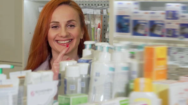 Mujer atractiva sonriendo, eligiendo productos médicos de la estantería en la farmacia — Foto de Stock