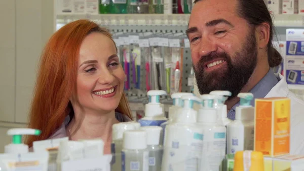 Handsome bearded pharmacist giving his female customer requested product