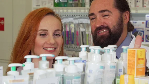 Hermosa mujer hablando con el farmacéutico, mientras que la selección de productos para comprar — Foto de Stock