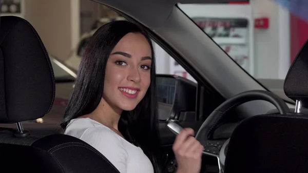 Schöne glückliche Frau sitzt in ihrem neuen Auto und zeigt Autoschlüssel in die Kamera — Stockfoto
