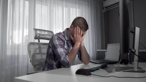 Freelancer masculino perturbado sentado na frente de seus computadores — Fotografia de Stock
