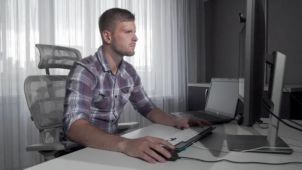 Przystojny to pracownik biurowy przy użyciu dwóch komputerów pracujących nad projektem — Zdjęcie stockowe