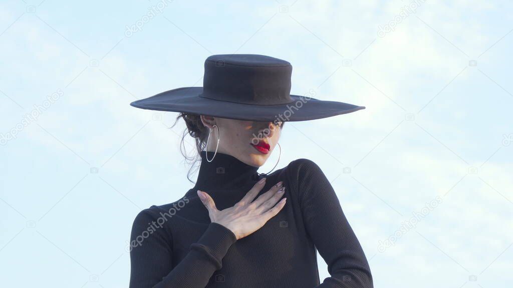 Beautiful mysterious woman in black hugging herself sensually
