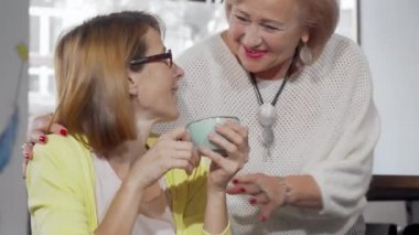 Olgun bir kadın, yaşlı annesiyle kahve dükkanında buluşuyor.