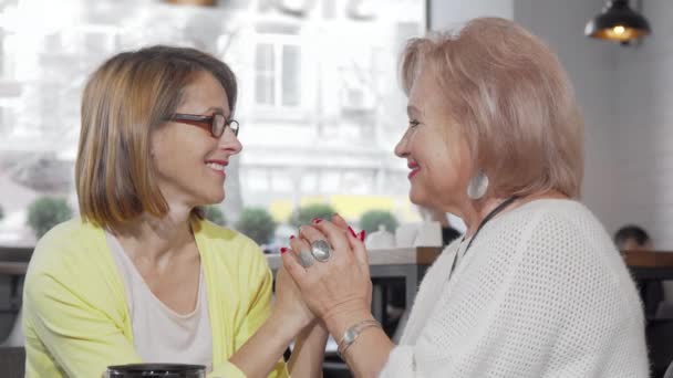 Lycklig äldre kvinna håller hand med sin mogna dotter och skrattar — Stockvideo