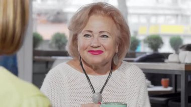 Yetişkin kızından hediye alan son sınıf mutlu bir kadın.