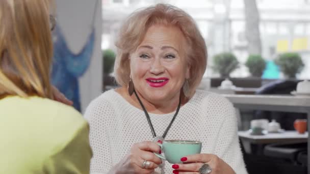 Bella donna anziana che ride parlando con sua figlia davanti a una tazza di tè — Video Stock