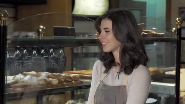 Charmante vrouwelijke bakker glimlachend naar de camera in haar bakkerij winkel — Stockvideo