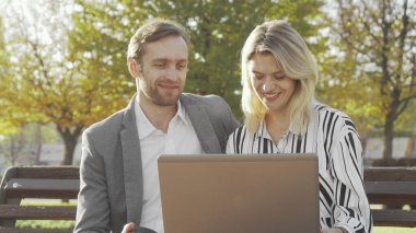 Parkta dizüstü bilgisayar kullanan iki iş arkadaşı.