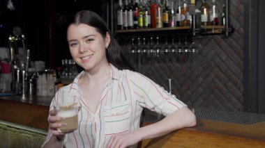 Çekici kadın kameraya kokteyl bardağıyla kadeh kaldırıyor.