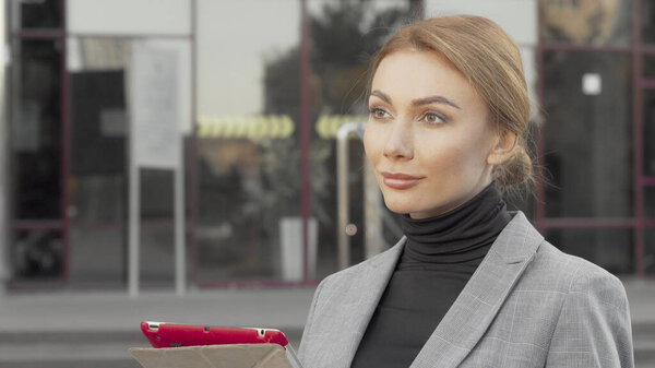 Красивая деловая женщина, использующая цифровой планшет на открытом воздухе в городе