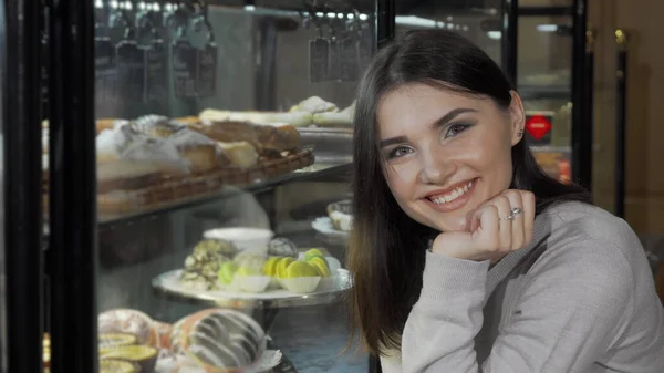 Чарівна молода жінка посміхається до камери під час покупки в пекарні — стокове фото