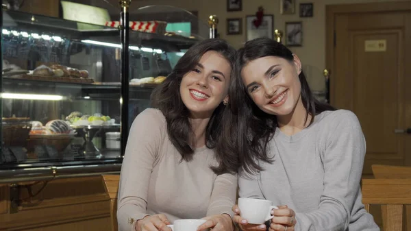 Două tinere prietene fericite zâmbind camerei de la cafenea — Fotografie, imagine de stoc