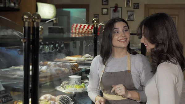 Una joven encantadora hablando con un cliente en su panadería — Foto de Stock