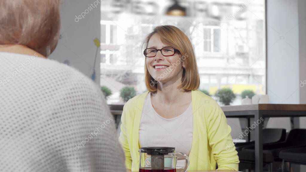 Cheerful mature woman giving a gift to her senior mother