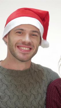 Neşeli bir çift, Noel Baba şapkaları ve rahat kazaklarla süslenmiş, yeni dairelerinin anahtarlarını parlak beyaz bir arka planda gururla sergiliyorlar. Işıldayan gülümsemeleri ve sıcacık kucaklamaları aşkın özünü, bayram neşesini ve taze başlangıçları yayıyor.