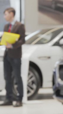 Kendine güvenen bir araba satıcısı ve bir erkek müşteri, modern bir otomobil galerisinde güven ve ortaklığı somutlaştıran sıkı bir tokalaşmayı paylaşıyorlar. Sahne, arka planda parıldayan beyaz ve mavi arabalarla güçlendiriliyor.