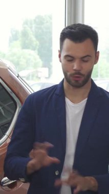 İki şık genç adam, modern bir bayilikte heyecan ve dostluk saçan çarpıcı yeni bir araba hakkında coşkulu bir sohbete girişiyor. Sergi salonu parlak araçlar ve parlak ışıklandırmayla parıldıyor, davetkar bir atmosfer yaratıyor.