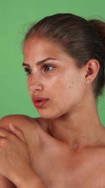 Göz kamaştırıcı, güneş yanığı bir ten rengine sahip genç bir kadın zarif poz veriyor, çıplak omuzları canlı yeşil bir arka plana karşı doğal güzelliğini vurguluyor. Kendine güveni ve yumuşak, cezbedici dudakları şehvet ve zarafet saçıyor.