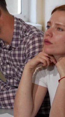 Kızıl saçlı bir kadın bir sınıf masasında oturur, çatık kaşları ve delici bakışları zorlu bir okul projesiyle boğuşurken hayal kırıklığı ve kararlılığın bir karışımını yansıtır. Çevredeki sınıf arkadaşları gözle görülür bir gerilim yaratıyor.