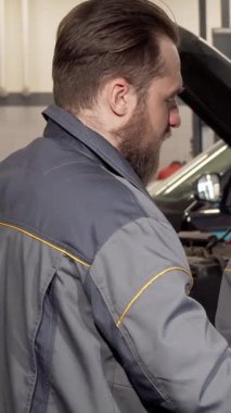 Canlı kızıl saçlı yetenekli bir bayan tamirci ve odaklanmış erkek arkadaşı otomotiv dünyasında özenli bir şekilde bir araba motorunu inceliyor. Şık gri üniformalı kadın, not defterine titiz notlar alır.