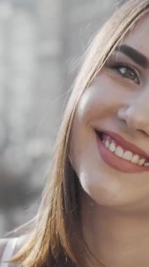 Neşeli genç bir kadın bulaşıcı mutlulukla ışıldıyor, ışıl ışıl gülüşü şehrin hareketli sokaklarına karşı sahneyi aydınlatıyor. Bu büyüleyici an onun kaygısız ruhunu özetliyor. Enerjisini ve gençlik cazibesini yansıtıyor.