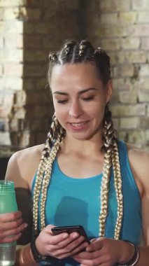 Canlı bir spor salonu ortamında, akıllı telefonlarını kontrol ederken üç zinde kadın kahkahalarını paylaşıyor, fitness ve arkadaşlığın mükemmel bir karışımını sergiliyorlar. Renkli spor kıyafetleri ve ışıl ışıl gülümsemeleri atmosferi aydınlatıyor.