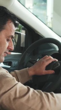 Arka koltuklardan, koyu saçlı kendine güvenen bir adam arabalara yüksek teknolojili özellikler yüklüyor, dikiz aynasını ayarlıyor ve coşkuyla düğmelere basıyor. Sıcak gülüşü heyecan saçıyor. Seçme heyecanını mükemmel bir şekilde yakalıyor.