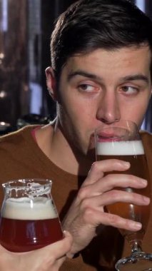 Çekici bir adam ve kız arkadaşı neşeli bir kahkahayı canlı bir barda el sanatları biralarını tokuştururken, özel bir gecede aşklarını kutlarken paylaşıyorlar. Sıcak, davetkar atmosfer kahkaha sesleri ve bardakların tıkırtısıyla doluydu.