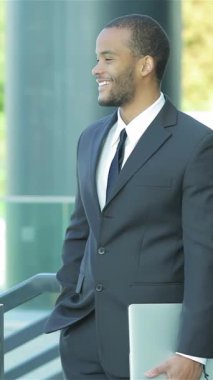 İki gülümseyen iş adamı canlı bir sohbete dalarken canlı bir karşılaşma gerçekleşir. Keskin elbiselerine güven yayarlar. Modern mimarinin gösterişli arkaplanı işbirliği ve başarı atmosferini güçlendirerek,