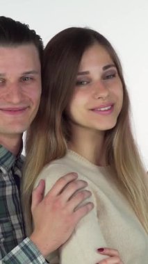 Hoş genç bir çift sıcak bir kucaklaşmaya sarılmış, düşünceli bir şekilde yanlarındaki yumuşak beyaz alana bakıyorlar. Yakışıklı adam, ışıl ışıl gülümseyen, güzel kız arkadaşını kucaklıyor, bu samimi anda sevgi ve neşe saçıyor.