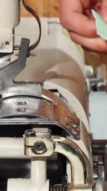 Tutkulu bir kunduracı, kaliteli bir dikiş makinesi kullanarak titizlikle deriden canlı bir parça hazırlar ve zarif ayakkabıların ardındaki sanatçılığı vurgular. Görüntü, odaklanmış elleri iş yerinde yakalar. Karmaşık ayrıntıları ve özveriyi gözler önüne serer.