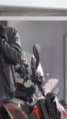 Gülümseyen beyaz bir adam çağdaş bir bayilikte çarpıcı bir siyah motosikletin yanında dururken canlı bir telefon görüşmesi yapar. Şık ekose gömleği ve deri ceketi motosiklet çizgilerini mükemmel bir şekilde tamamlıyor.