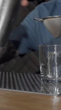 Yetenekli bir erkek barmen bardağa kremalı kokteyl dökerek fevkalade bir miksoloji yeteneğini ön plana çıkarıyor. Parmaklıklar, atmosferi, retro dekoru ve sıcak ışıklandırmasıyla, canlı bir gece hayatı deneyimi yaratıyor.