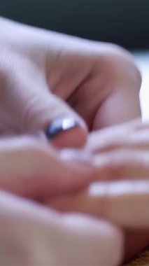 Yakından bakıldığında, bir güzellik uzmanının becerikli elleriyle müşterinin parmaklarına nazikçe masaj yaptığı, sakin bir manikür salonu atmosferine sarılı olduğu görülüyor. Sahne lüks ve rahatlama yayıyor, mükemmel manikürlü tırnaklar ve yumuşak ciltler, hepsi hazır.