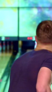 Yakışıklı sarışın bir adam, kendine güveni tam, canlı bir bowling topunu kulvardan yuvarlamaya hazırlanıyor, kalan iğnelere odaklanmış bakışları. Renkli ışıklarla aydınlatılan canlı bowling salonu, oyunun heyecanını arttırıyor,