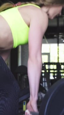 Bu büyüleyici arka planda, canlı neon bir üst ve parlak siyah tozluklu fit bir sporcu modern bir spor salonunda ağır bir halterle kaldırma kuvvetini gösteriyor. Atmosfer enerjiyle uğulduyor, bağlılığını vurguluyor.