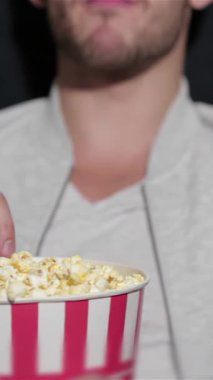 Loş bir sinemada rahat koltuklara kurulmuş neşeli bir çift, büyük çizgili patlamış mısır kovasını paylaşıyor, kahkahaları havada yankılanıyor. Büyüleyici atmosfer heyecanla uğulduyor, kendilerini filme daldırıyorlar, etrafları arkadaşlarla çevrili.