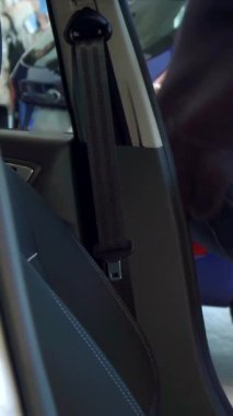 Şık, genç, bakımlı sakallı beyaz bir adam kemerini parlak, modern bir arabada takarken neşe saçıyor. Son model tasarım elementleriyle süslenmiş canlı iç mekan heyecan verici yeni sürüş yolculuğunun heyecanını arttırıyor.