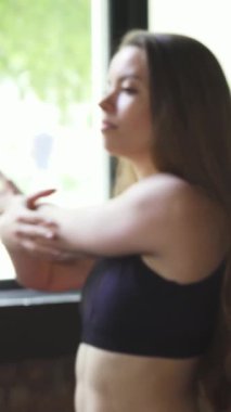 İki kararlı genç kadın, biri örgülü saçlı, diğeri de dalgalı bukleli, kollarını güneşli bir spor salonunda uzatıyorlar, enerji ve odaklanma saçıyorlar. Bu canlı sahne takım çalışmasını ve motivasyonunu somutlaştırıyor, spor yapmaya olan bağlılıklarını vurguluyor ve