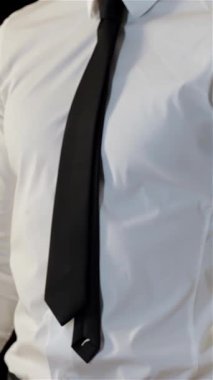 Genç beyaz bir adam avuçlarını bir araya getirip güçlü bir onay ve başarı hissi yayıyor. Gıcır gıcır beyaz bir gömlek ve keskin siyah bir kravat giyer. Profesyonelliği ve pozitifliği somutlaştırır. Mükemmel bir şekilde özünü yakalar.