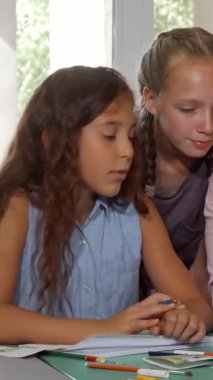 Coşkulu bir grup çocuk, neşeli resim öğretmenlerinin çizim becerilerini gösterip yaratıcılığını ateşlemesini izlerken canlı bir sahne ortaya çıkıyor. Olgun bayan öğretmen, sıcaklık ve neşe saçarak, onu büyüleyen öğrencilerine ilham verir.