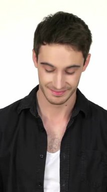 Sıradan siyah gömlekli ve beyaz atletli çekici bir genç adam düşünceli bir şekilde poz veriyor, gözleri yavaşça yere eğiliyor. Gövdesinde hafif bir köpük ve yumuşak beyaz bir arka planla, kendine güveni yayar ve izleyicileri kendi anına davet eder.