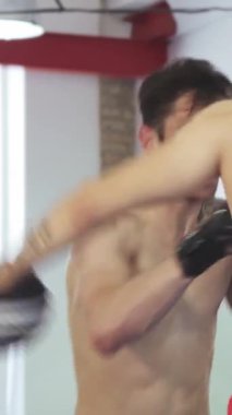 Renkli eğitim ekipmanlarıyla dolu canlı bir spor salonunda kararlı bir kickboksör güçlü yumruklarını koçunun gözü önünde biler. Eğitimlerinin yoğunluğu havada yayılıyor, sporcuların kaslı fiziği ve...