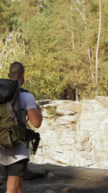 Uçurumun kenarında el ele duran genç bir çift, göz kamaştırıcı dağ manzaraları ve yemyeşil manzaralarla çevrili. Esmer adam ve kadın, her ikisi de canlı yürüyüş kıyafetleri içinde, sıska kız parmaklarının ucunda dururken yürekten kucaklaşırlar.