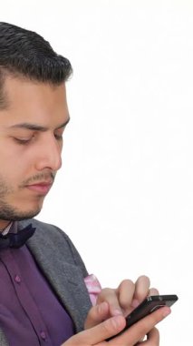 Şık takım elbiseli ve şık papyonlu genç bir işadamı, akıllı telefonuyla derinden meşgul, kendine güven ve profesyonellik saçıyor. Odaklanmış tavrı ve ciddi ifadesi teknolojinin dinamik etkileşimini yansıtıyor.