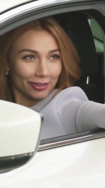 Çekici, dalgalı saçlarıyla ışıldayan genç bir kadın zarif, modern arabasından selfie çekerken mutluluk saçıyor. Canlı sahne, onun yeni sahiplik heyecanını özetliyor, teknoloji ve sevinci, kendini ifade etmenin keyifli bir anında birleştiriyor.