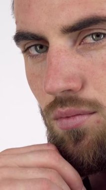 Dikkat çekici derecede yakışıklı, bakımlı sakallı ve delici gözlü bir adam, eli çenesinde dinlenirken, dikkatlice mesafeye bakıyor. Bu samimi portre, modern erkekliğin ve özgüvenin özünü yansıtıyor, izleyicileri keşfetmeye çağırıyor.