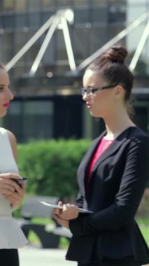 Kararlı genç bir iş kadını dışarıda duruyor, tabletle yakından ilgilenirken meslektaşları sohbet ediyor. Bu canlı sahne modern iş işbirliğinin nabzını özetliyor. Sinerjiyi ve enerjiyi vurguluyor.