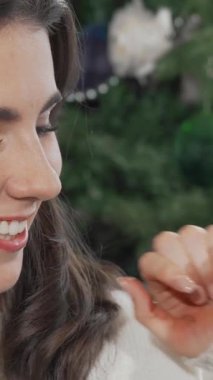 Işıl ışıl bir kadın, neşeli bir şekilde kameraya gülümsüyor, neşeli bir şekilde oyuncak Noel Baba 'yı kucaklıyor, neşeli ruhu somutlaştırıyor. Parıldayan ışıkların ve güzel süslenmiş bir Noel ağacının arkasına kurulmuş bu büyüleyici sahne sıcaklık ve sıcaklık yayıyor.